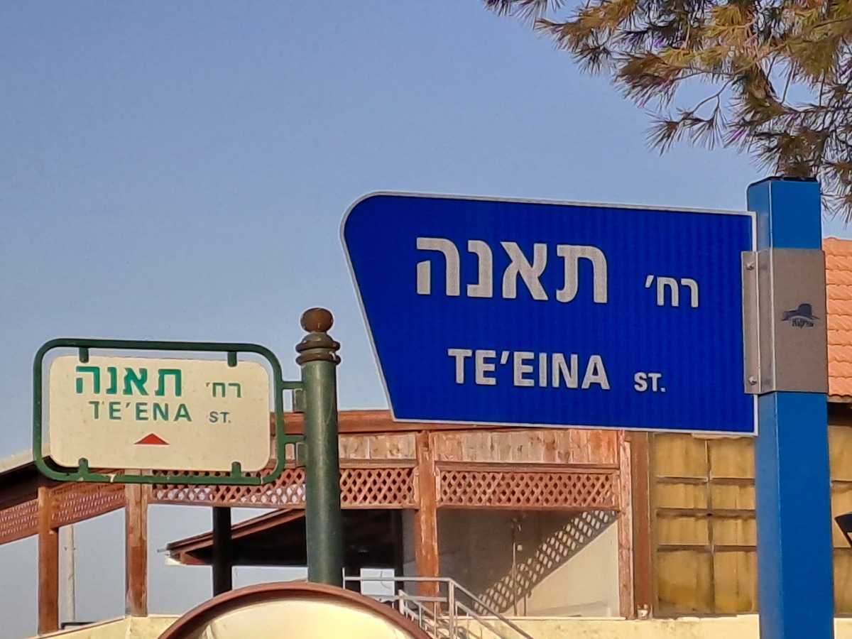 השלט החדש (כחול) לצד השלט הישן (צבעוני) לפני הורדתו. צולם בשכונת ה-34