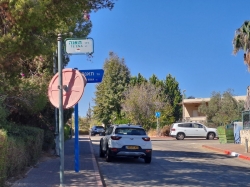 השלט החדש (כחול) לצד השלט הישן (צבעוני) לפני הורדתו. צולם בשכונת ה-34